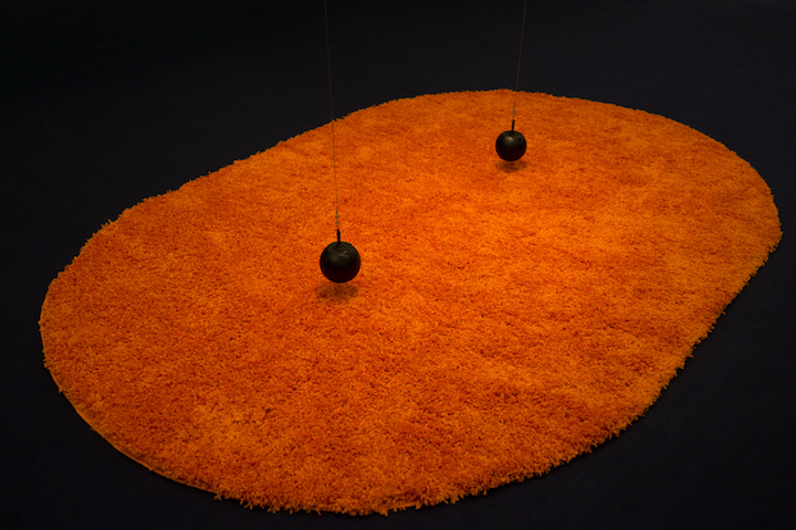 pomarańczowy dywan, nad nim wiszące dwie żeliwne kule