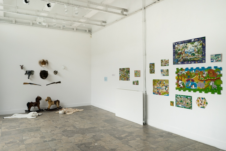 Widok wystawy. Po lewej instalacja z pluszowych poroży, po prawej na ścianie znajdują się puzzle ze zdjęciami zwierząt w cyrku.
